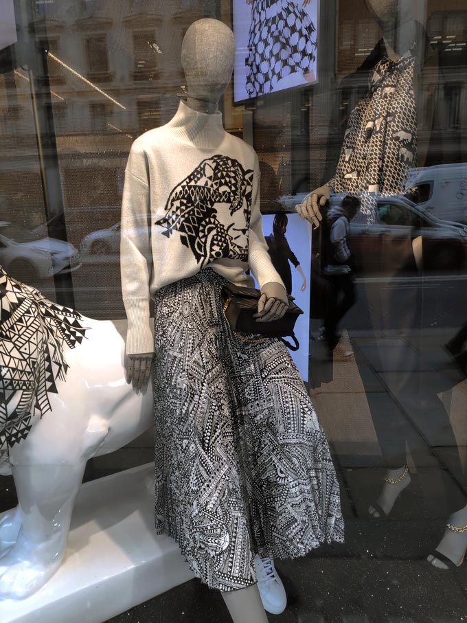 Two mannequins dressed in stylish black and white outfits part of a Hugo Boss shop window.