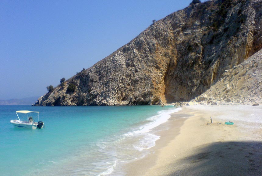 Just one of the many turquoise water beaches of Kefalonia with a small rental motor boat moored to the left. Image by Velvet Karatzas.