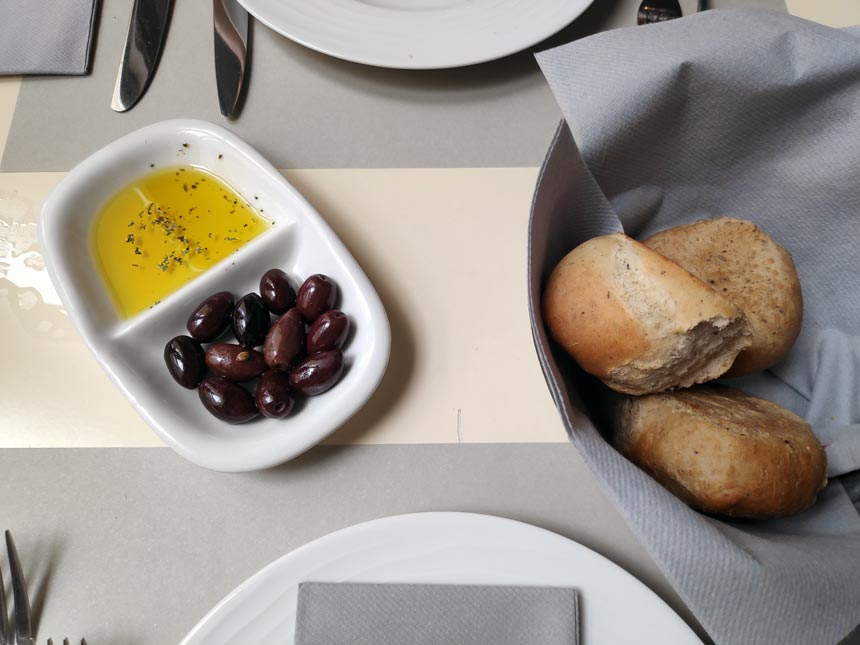 Olives and olive oil along with bread buns as an horderve.