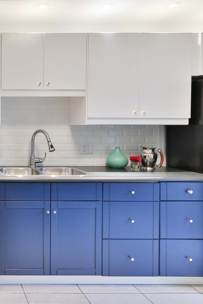 Partial view of a kitchen with top white cabinetry and bottom blue cabinetry.