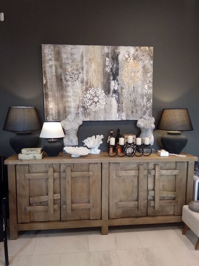 Home improvement ideas - an accent wall. A large sideboard with an artwork on top of it, against an almost black wall. Decor pieces and black table lamps complete the synthesis.