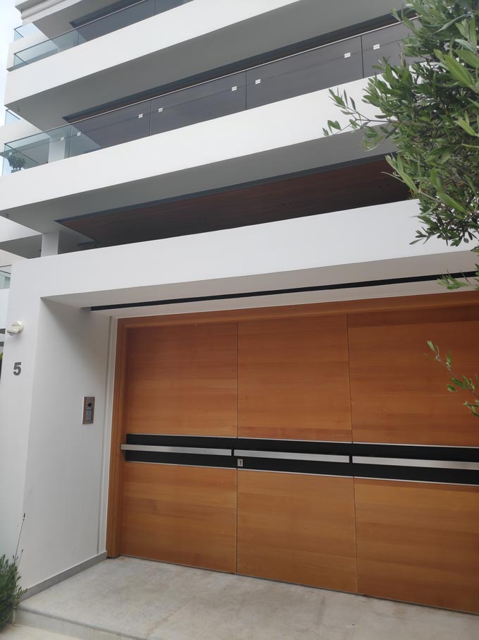 An exterior wooden door entrance to a building block of flats in Athens. Image by Velvet.