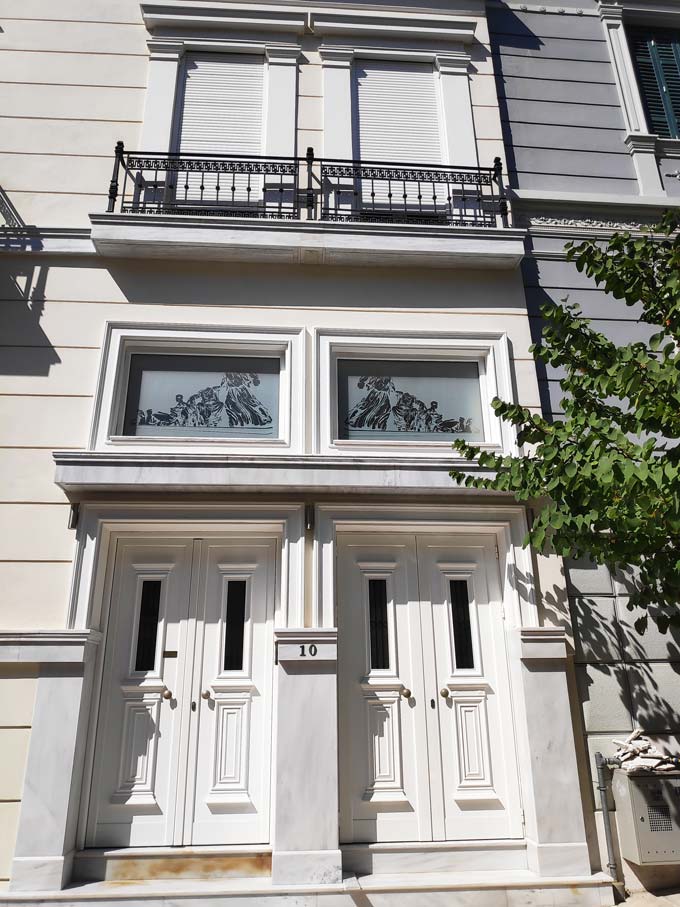 Two adjacent white entrance doors of a neoclassical building.