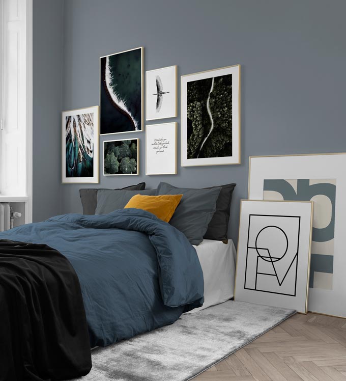 A contemporary bedroom in a grey blue color palette, featuring a gallery wall including some prints with typography.