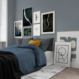 A contemporary bedroom in a blue color palette featuring a gallery wall that includes typography prints. Image by Desenio.