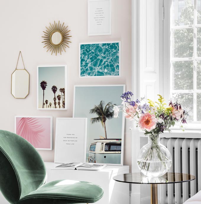 Partial view of a bright living space featuring a gallery wall that includes typography prints. Image by Desenio.