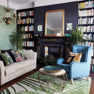 Loving the mix of green and mauve on the walls. A stylish living room with a purple accent wall and fireplace in mauve and bookcases on either side of it. Image by Dunelm.