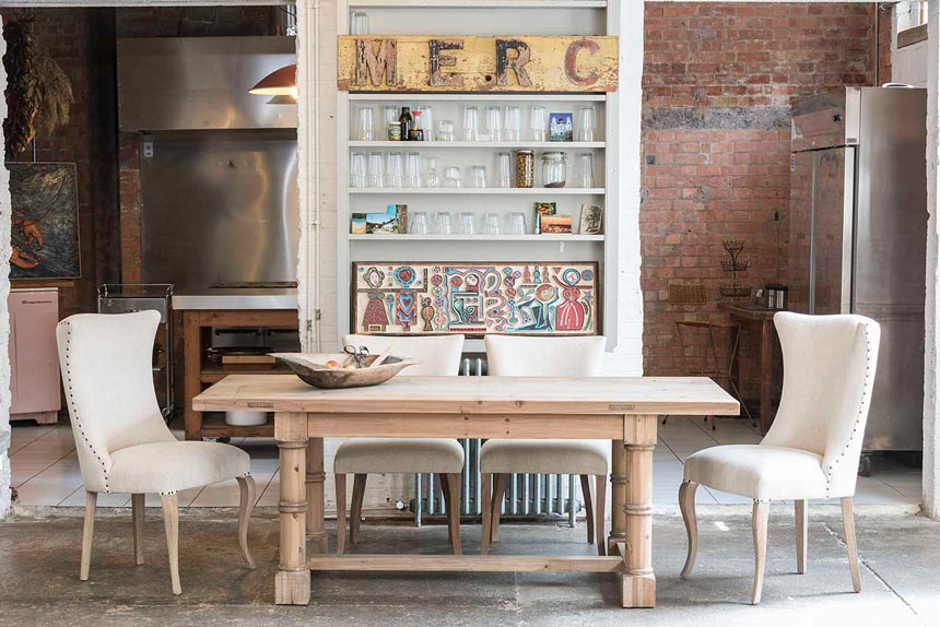 What a beautiful dining space - a fusion of industrial style with inox details and exposed brick wall accents and rustic elements due to this fab looking dining table combined with white dining chairs. Image by Houseology.
