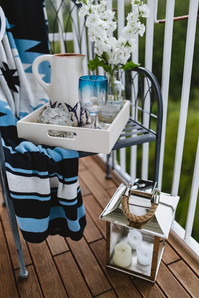 A narrow balcony with a chair and lots of nautical theme decor including a lantern.