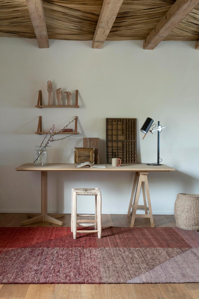 A red pattern area rug in front of a rustic home office. Image via Nest.co.uk.