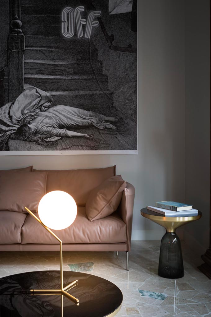 View of a vignette with a leather sofa, a glass side table and the IC T1 high table lamp designed by Michael Anastassiades on a glass coffee table. Image via Nest.co.uk.