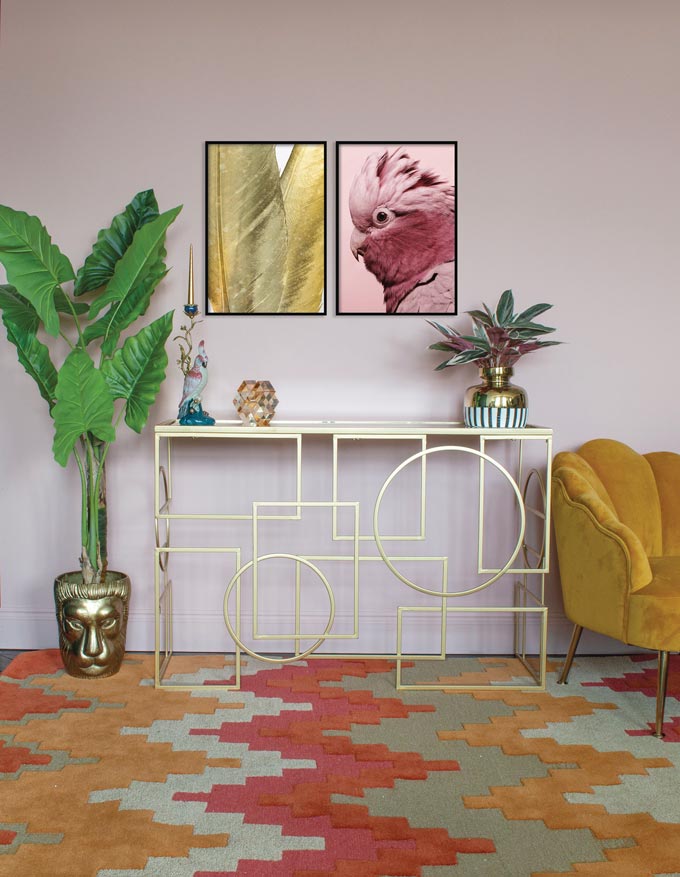 An eye-catching chevron pattern rug sets the mood for this contemporary vignette with mustard hues dominating the space, a tall plant in a golden planter, a velvet armchair next to a brass console table. Image via Audenza.