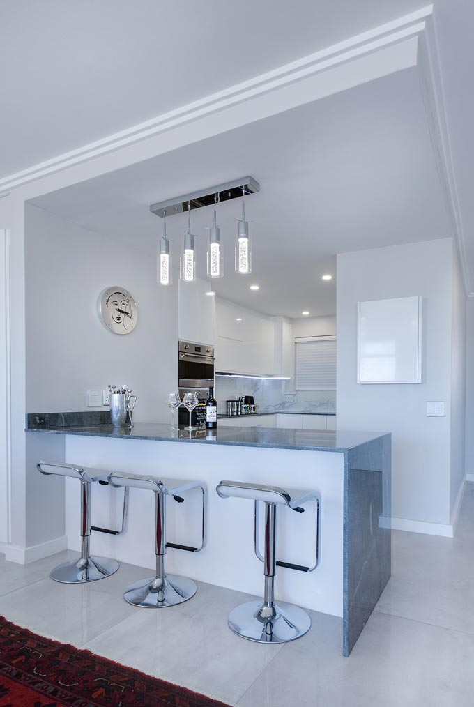 A modern minimalist kitchen with a bar bridge made of a grey marble.