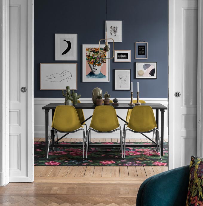 A stylish dining space featuring a blue accent wall with an art gallery. Image by Desenio.