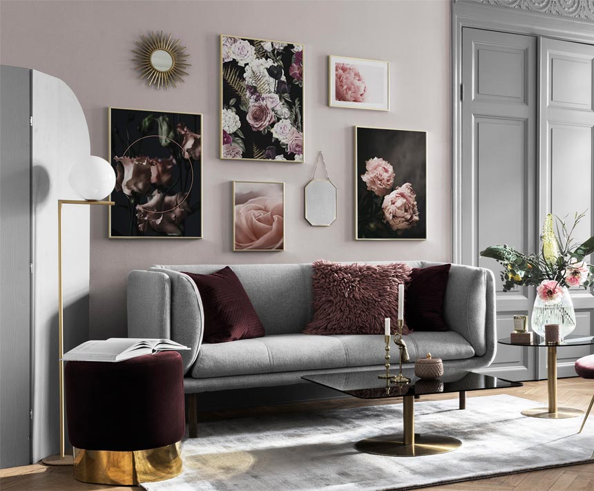 A perfect example of an art gallery wall in a stylish grey living room with burgundy accents, that sports a combination of art images hanging from a wall and mirrors. Image via Desenio.