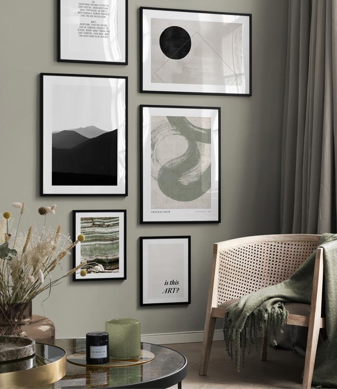 A gallery wall with art prints. A cane armchair with a muted green throw and a dark marble top round table with decor set the organic but eclectic vibe. Image via Desenio.