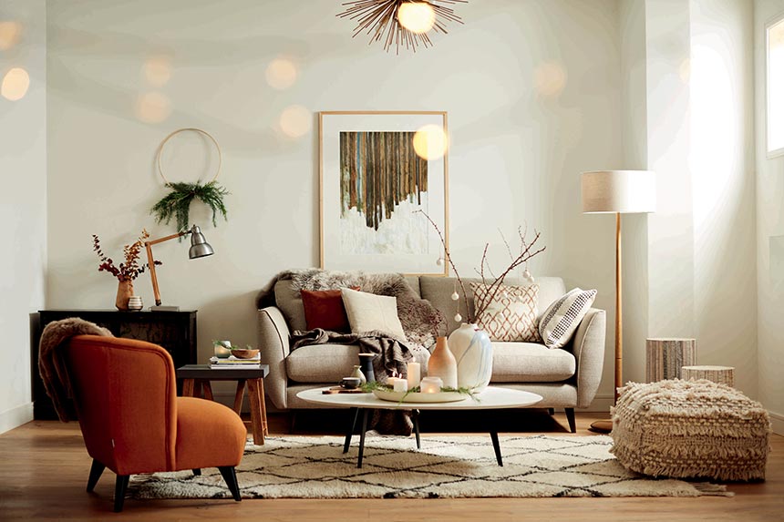 A contemporary living room with an off white sofa, paired with a rusty armchair. Image by DFS Furniture.