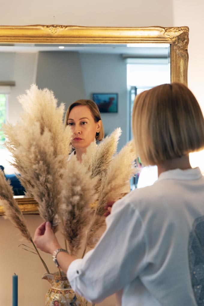 Velvet arranging a pampass grass arrangement in front of a vintage mirror.