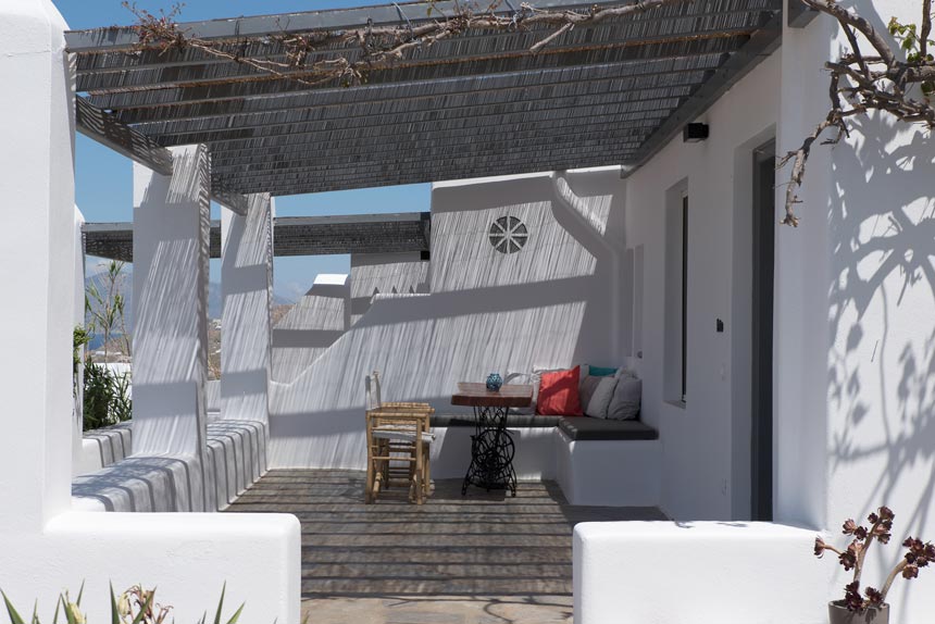 An outdoor veranda in a Cycladic dwelling with a pergola atop.