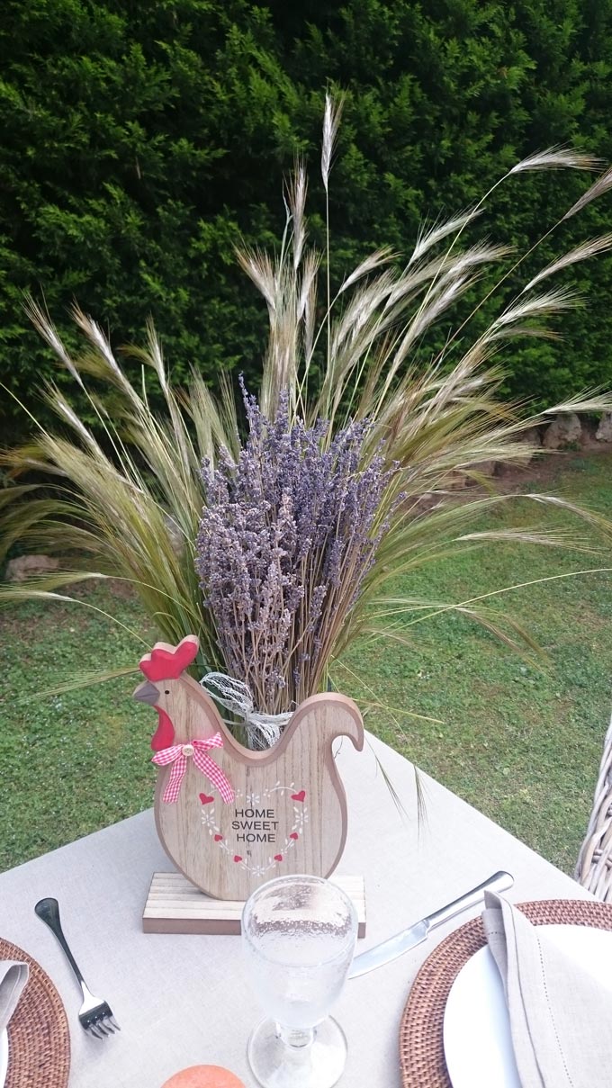 A rustic rooster decor piece used for Easter decoration on a table outdoors. Image by Velvet.