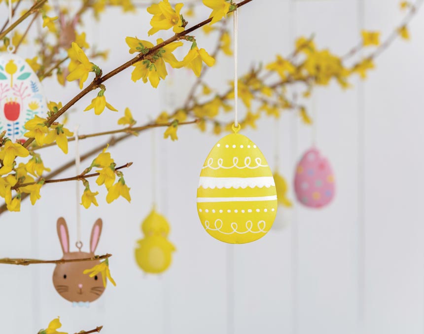 A branch in a vase and hanging Easter decor will give you the perfect centerpiece for you Easter table. Image via Rex London.