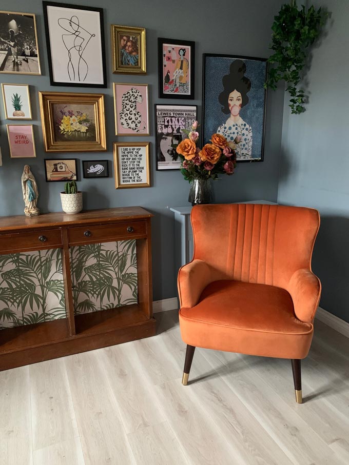 A burnt orange armchair looking great against the blue gray walls and the wooden sideboard, making a cozy vignette. Image by Cult Furniture.