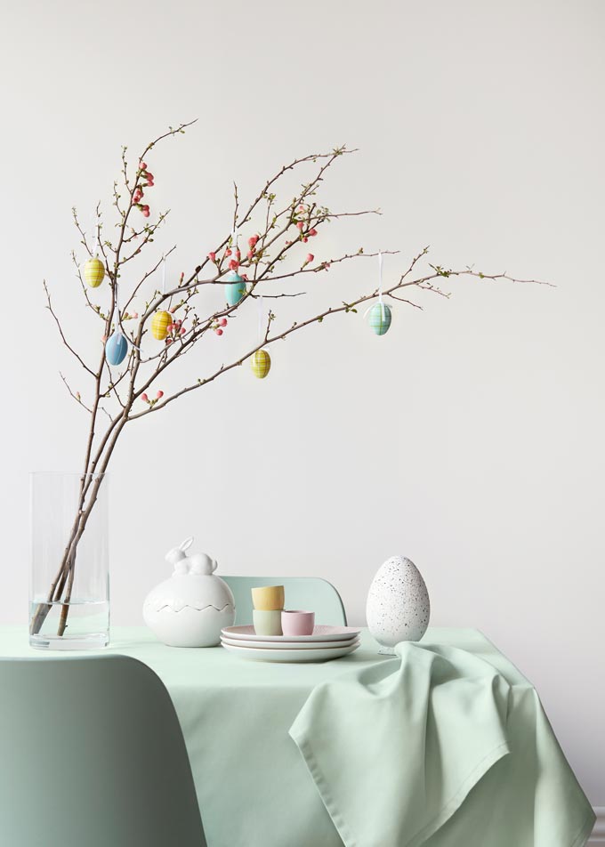 Easter decorations in pastel hues including a glass vase with a branch and eggs hanging from it. Image by John Lewis.