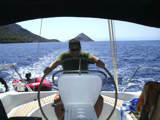 George behind a sailing boat's wheel