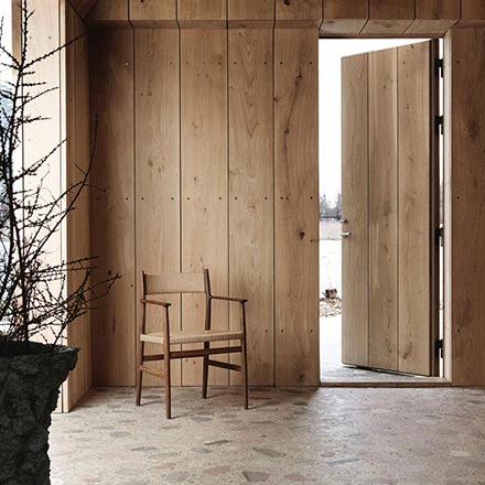 The Brdr. Krüger ARV Dining Chair standing in front of a wooden entrance. The noticeable attribute of this image is the color harmony and that includes the beige like terrazzo flooring. Image by Nest.