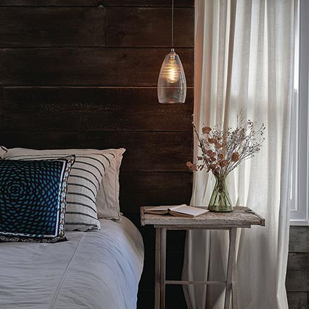 A Fritz Fryer pendant light over a side table creating a beautiful ambiance in this cozy bedroom. Image by Fritz Fryer.