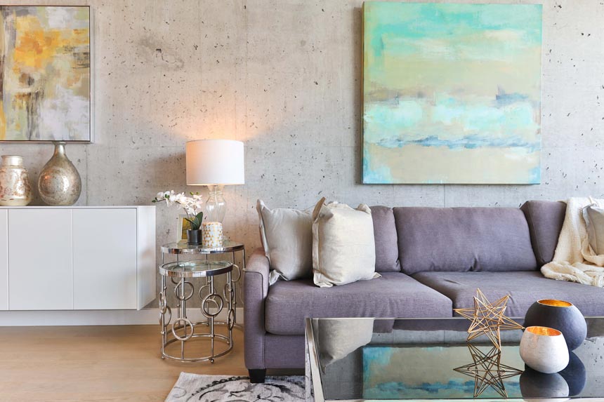 A stylish contemporary living room with beautiful artwork hangings and a large mirrored coffee table.