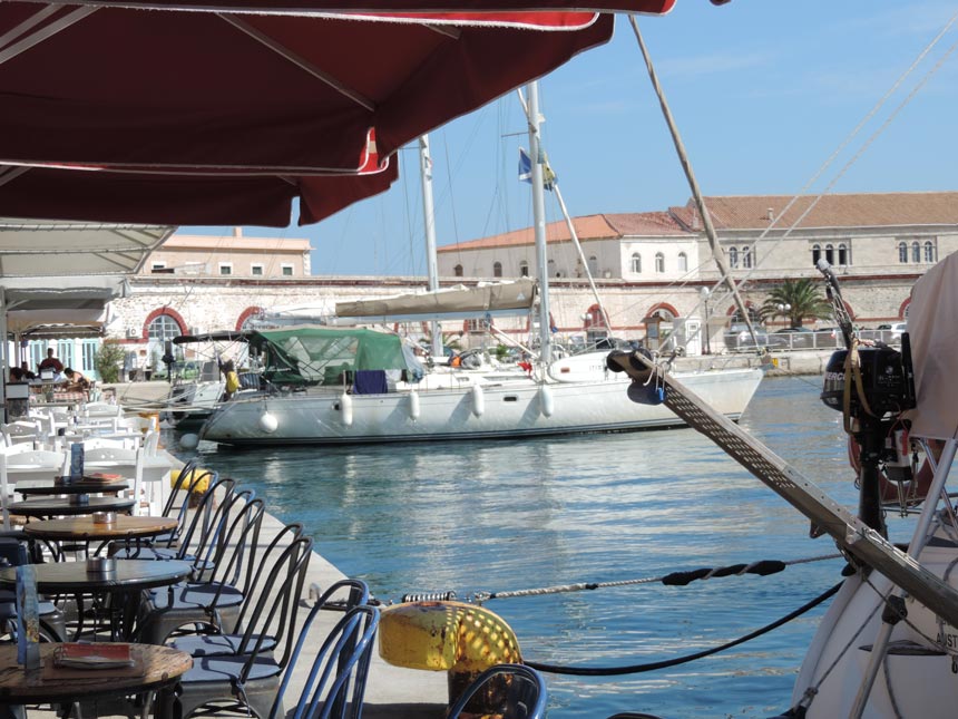 Partial view of the dock at Ermoupolis Syros with sailing boats docked and the Customs Office in the background. Image by Velvet.