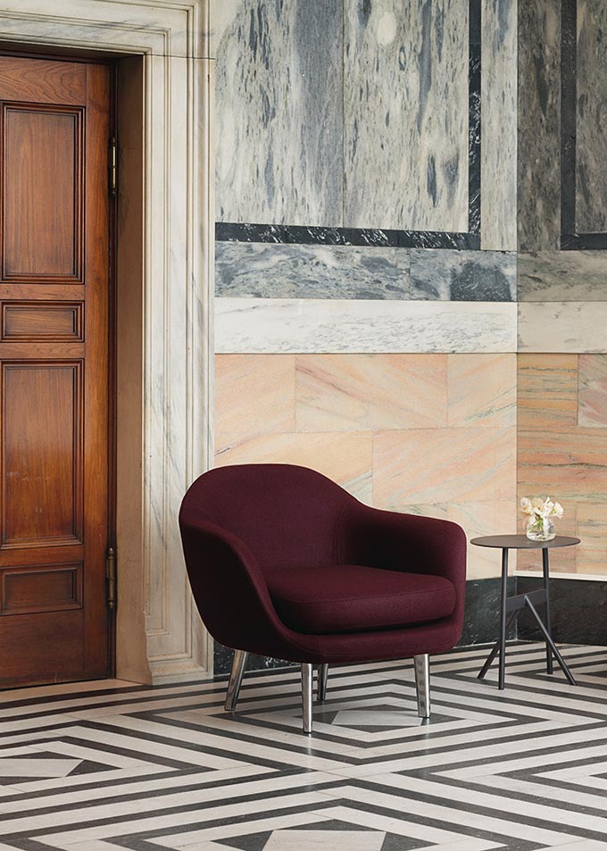 A comfy lounge chair in a prestigious looking space with marble flooring and wall cladding. Image by Nest.