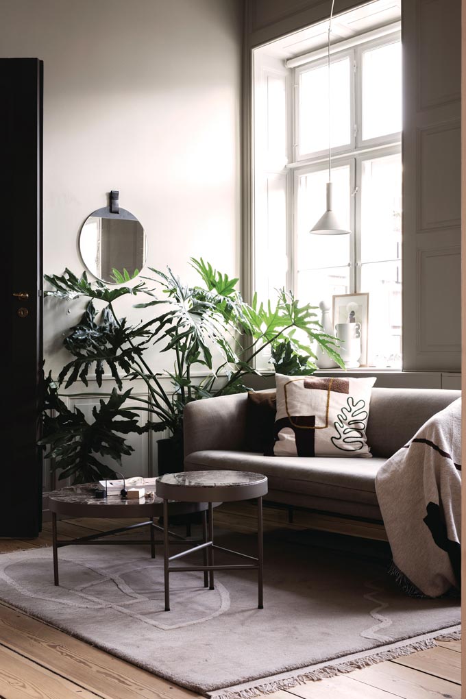 Ferm Living marble table in a contemporary muted beige living room with greenery and a large window. Image by Nest. 