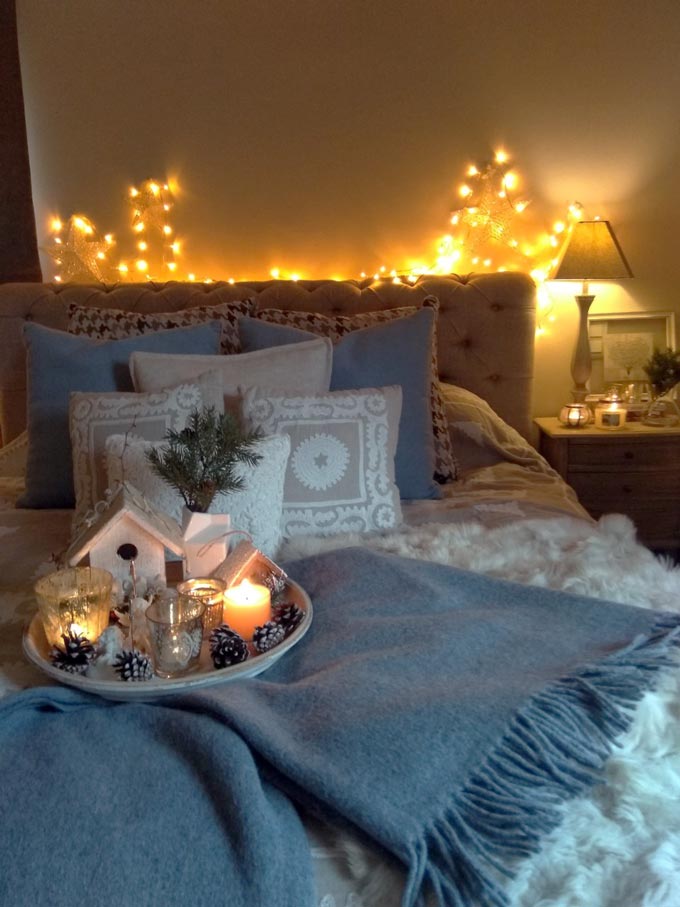 Elisabeth's bedroom with lots of decorative pillows on the bed, string of lights, candles and decor for that hygge.