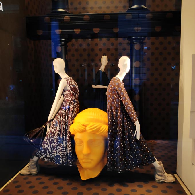 A window display from a women's store in Milan with three mannequins and a huge yellow bust. Image by Velvet.