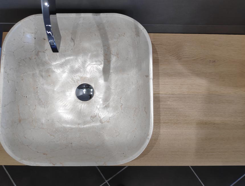 Bathroom improvement ideas - a statement washbasin. A stone wash basin atop a wooden counter.