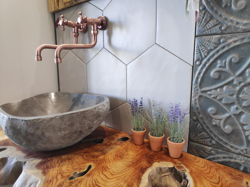 Bathroom improvement ideas - a statement washbasin. A stone wash basin on a rough rustic style counter and copper faucet.