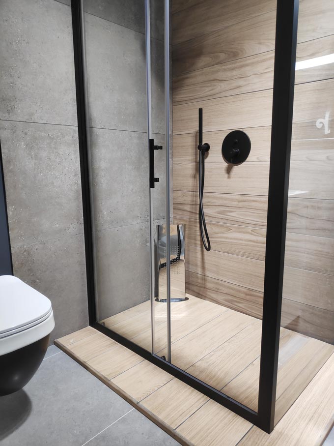 Bathroom improvement ideas: A contemporary shower with black finishes and wooden board flooring and wall tiling.