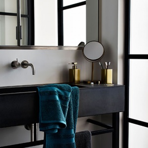 Dark poetry prevails in this beautiful bathroom with black details (faucet, sink, mirror frame). The brass accessories compliment the dark setting in the most elegant way. Image by Argos.