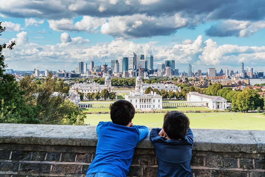 Two boys looking at the view of the Greenwich park, the Canary Wharf and Docklands in London.
