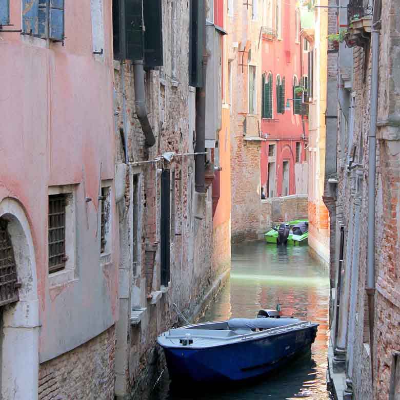 A small canal in Venice with colored buildings left and right