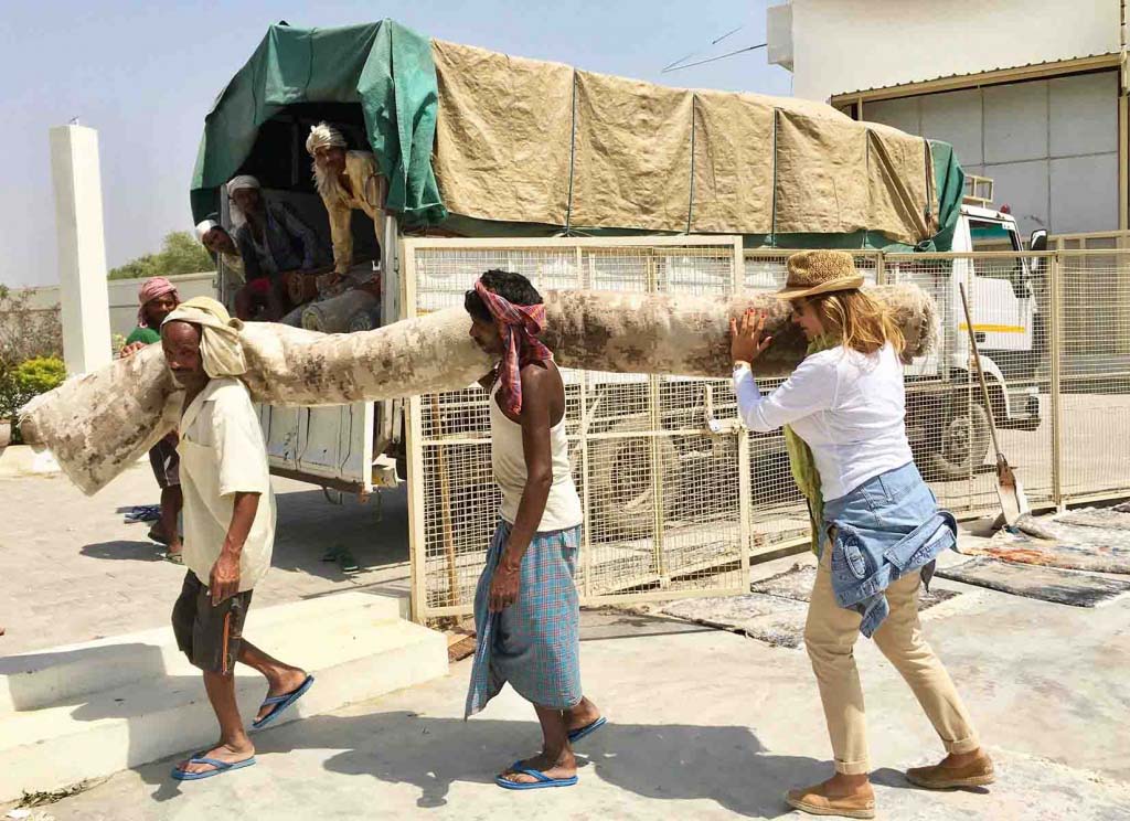 Two men and Argyriou carrying a rug onto a truck