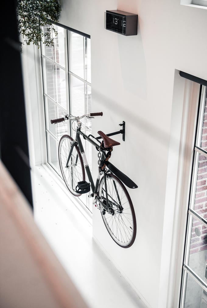 A bike hanging from a white wall.