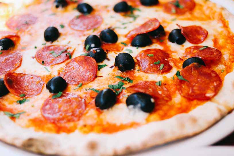 Detail of an Italian pizza with pepperoni and olives.