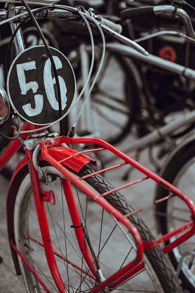 Detail of an old red bicycle with a black badge on it and the number 56 on it