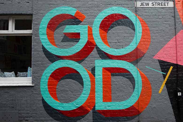 A gray xeterior wall with the word GO-OD written on it with graffiti in 3D teal lettering and red shadows