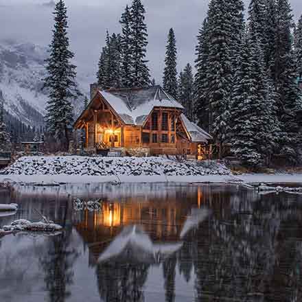 A cabin surrounded by nature in snow nearby a lake