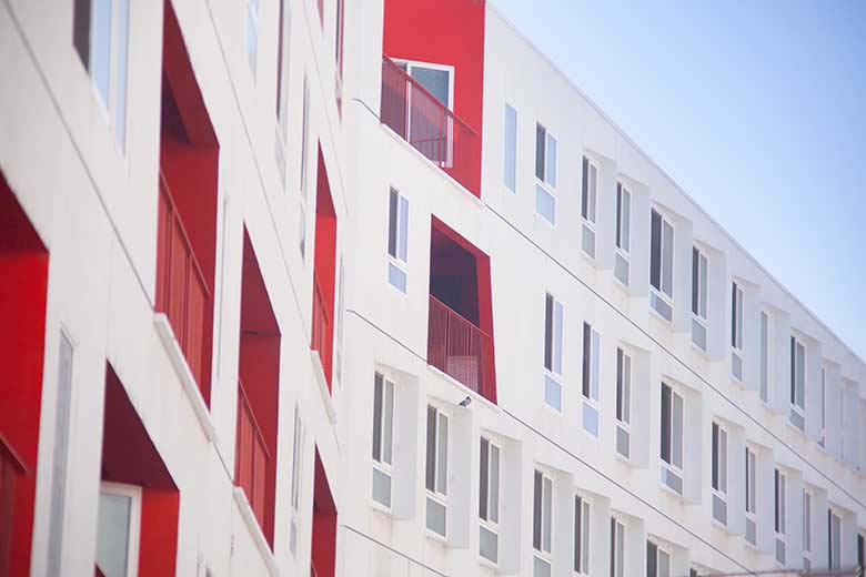 Exterior white facade of a building with some red details on a few walls and window inserts