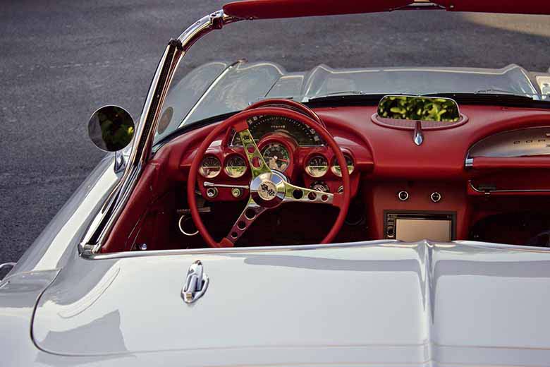 A white convertible car with a red leather dashboard and steering wheel